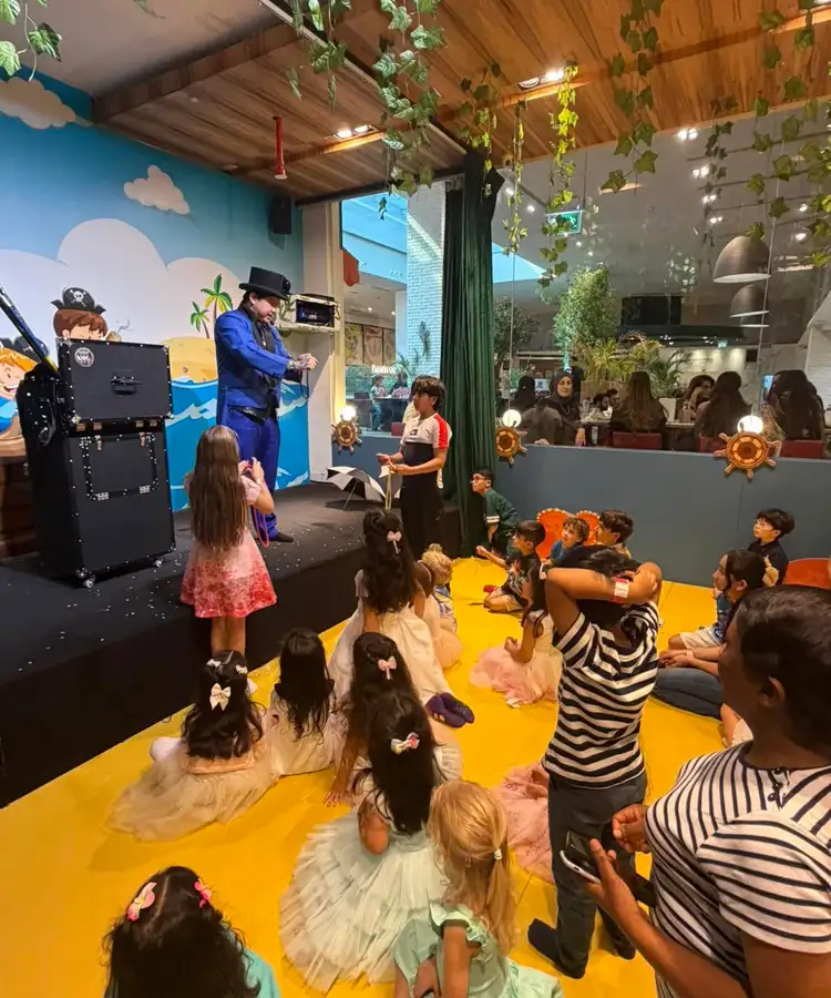 Magician on a small stage performing to children seated on the floor at a kids birthday venue in Dubai
