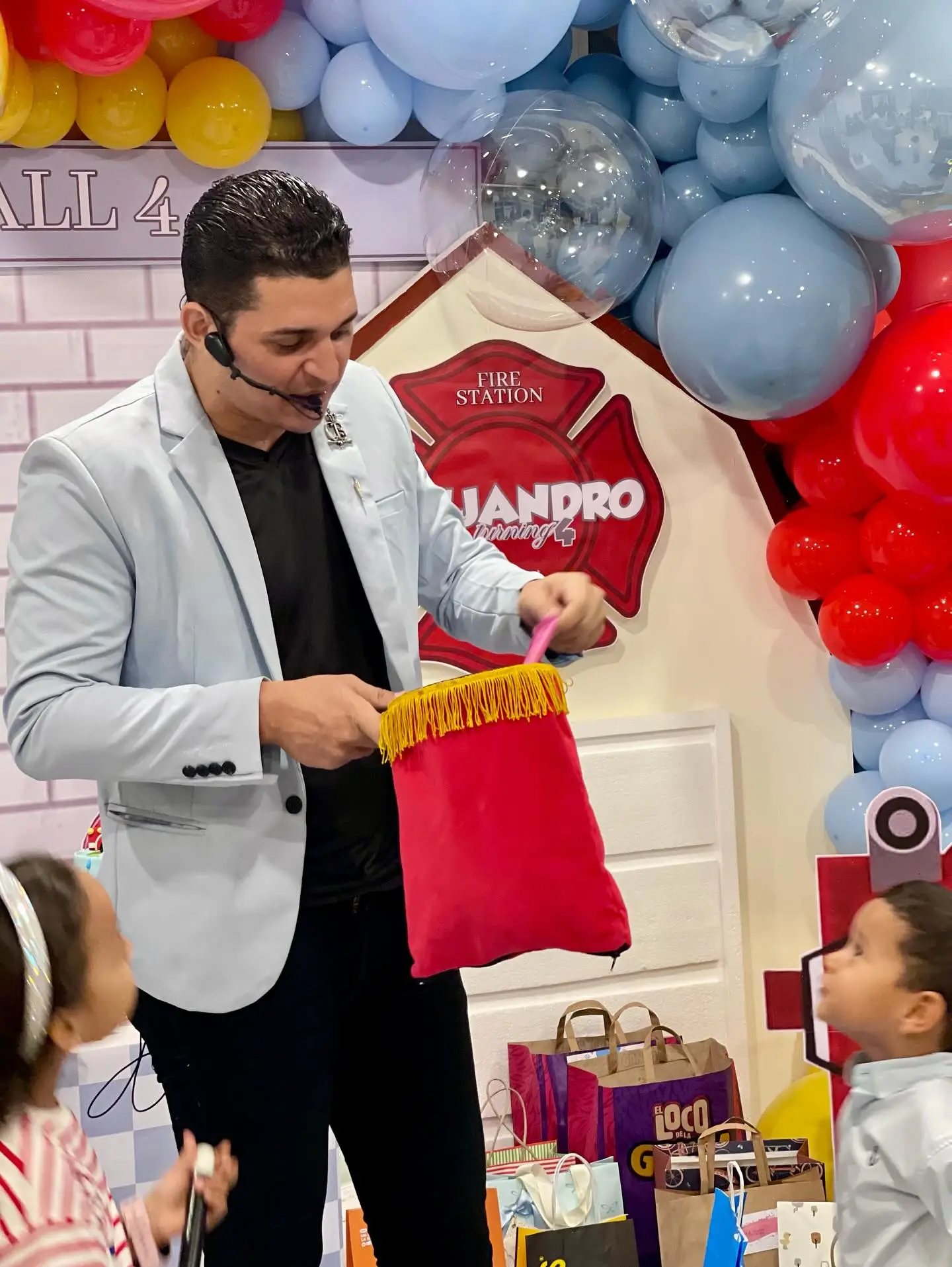 Kids party magician with a headset microphone performing a bag trick for young children in Dubai