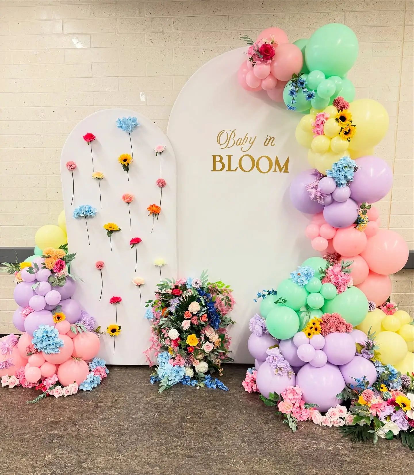 Baby in Bloom gender reveal backdrop with rainbow pastel balloons and colourful flowers