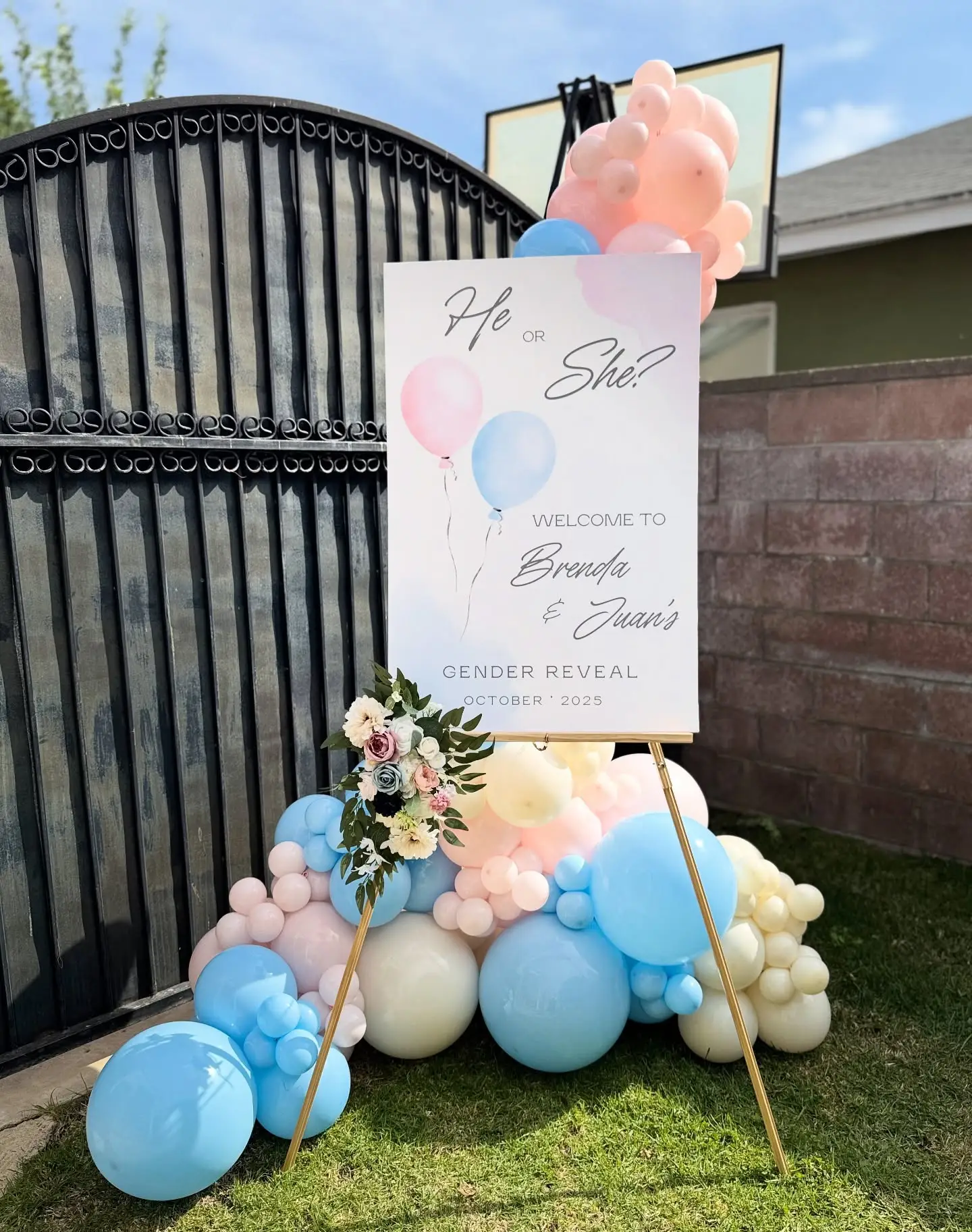 He or She? gender reveal welcome sign on an easel with a pastel balloon cluster and flowers