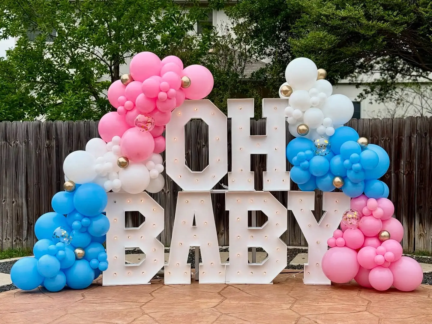 OH BABY marquee letters with pink and blue balloon clusters for a gender reveal party